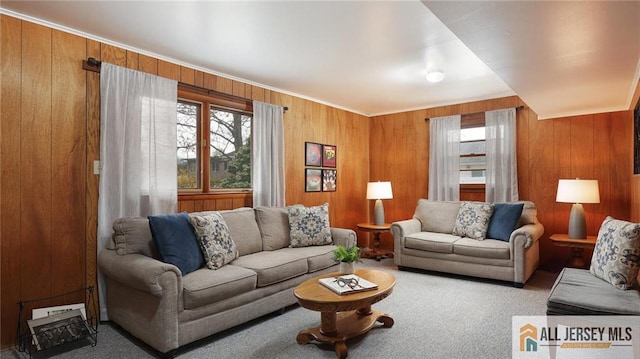 carpeted living room featuring wooden walls and ornamental molding