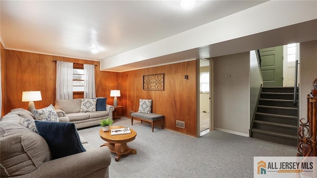 living area with stairway, wooden walls, visible vents, and carpet floors