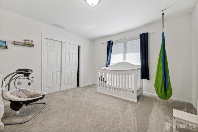 carpeted bedroom with baseboards, visible vents, and a closet