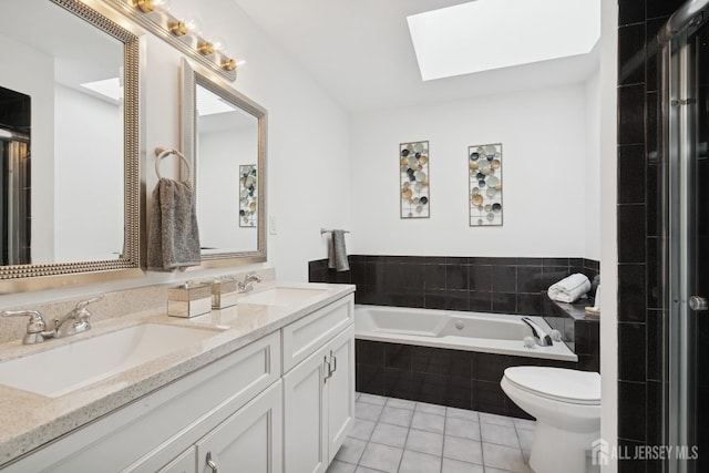 bathroom featuring a skylight, a garden tub, a sink, and tile patterned floors