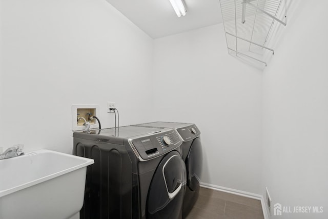 laundry area featuring laundry area, washer and clothes dryer, a sink, and baseboards