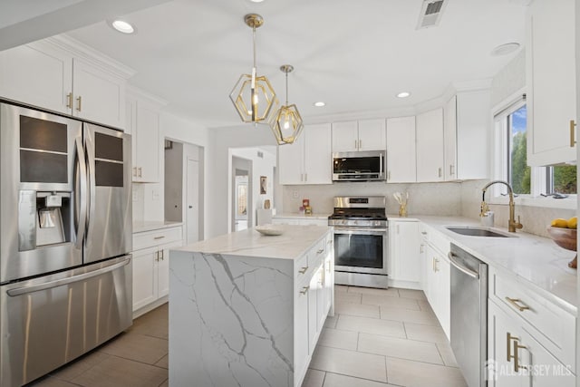 kitchen with a sink, visible vents, appliances with stainless steel finishes, backsplash, and a center island