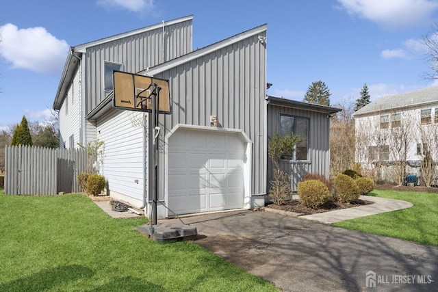 exterior space featuring fence, aphalt driveway, board and batten siding, and a yard