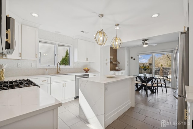 kitchen featuring light stone countertops, a sink, visible vents, appliances with stainless steel finishes, and a center island