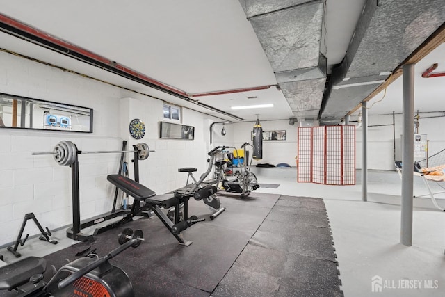 exercise area featuring concrete block wall and gas water heater