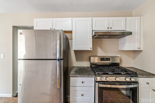 kitchen featuring under cabinet range hood, white cabinetry, baseboards, appliances with stainless steel finishes, and dark stone counters