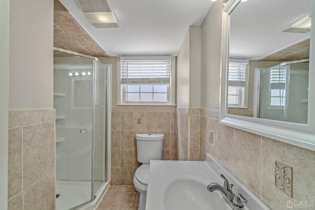 full bathroom with a stall shower, plenty of natural light, tile walls, and a sink