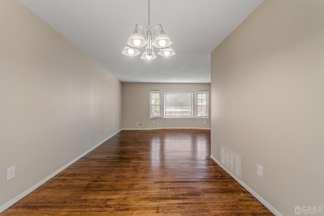 empty room featuring baseboards, visible vents, a chandelier, and dark wood-style flooring