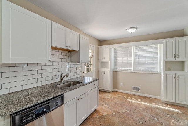 kitchen featuring visible vents, decorative backsplash, stainless steel dishwasher, a sink, and dark stone counters