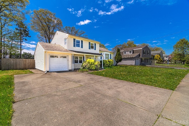 traditional home with driveway, an attached garage, fence, and a front yard