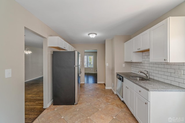 kitchen featuring tasteful backsplash, white cabinetry, stainless steel appliances, and a sink