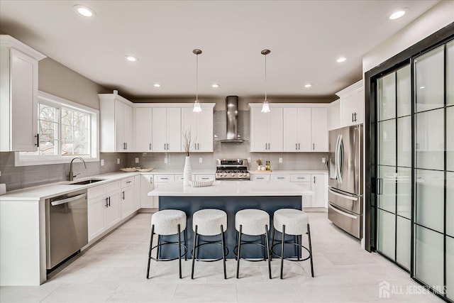 kitchen with wall chimney exhaust hood, stainless steel appliances, a center island, a sink, and a breakfast bar