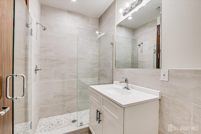 full bathroom featuring tile walls, a stall shower, and vanity