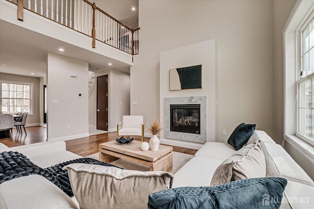 living area with baseboards, wood finished floors, a fireplace, and recessed lighting
