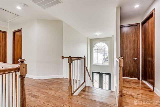 hallway with attic access, an upstairs landing, visible vents, and light wood-style floors