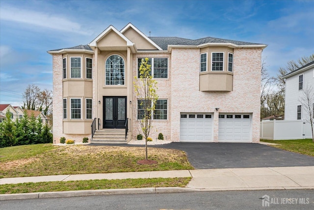 view of front of home with french doors, driveway, fence, a garage, and a front yard