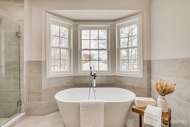 full bathroom with tile walls, a wealth of natural light, and a stall shower