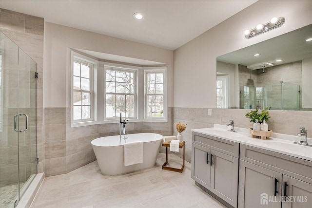 full bathroom with tile walls, a shower stall, and a sink