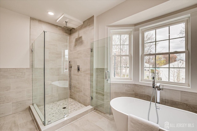 full bathroom with a shower stall, a soaking tub, and recessed lighting