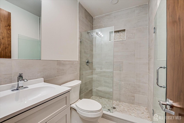 bathroom featuring tile walls, a stall shower, toilet, and vanity