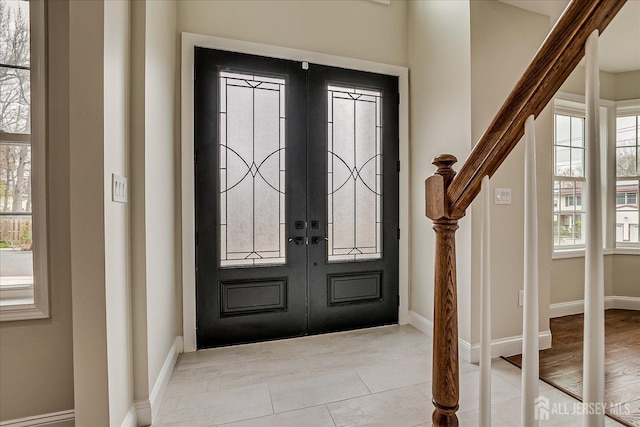 foyer entrance featuring plenty of natural light, french doors, and baseboards