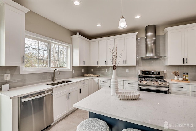 kitchen featuring a sink, stainless steel appliances, wall chimney exhaust hood, backsplash, and white cabinets