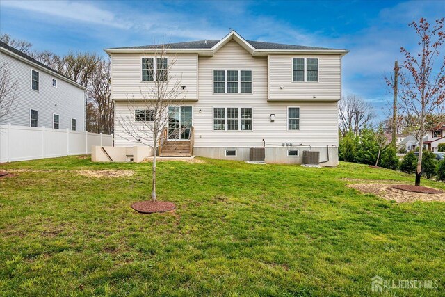 rear view of house with a yard, central AC, and fence