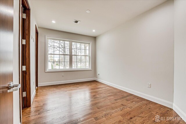 spare room with baseboards, light wood-style flooring, visible vents, and recessed lighting
