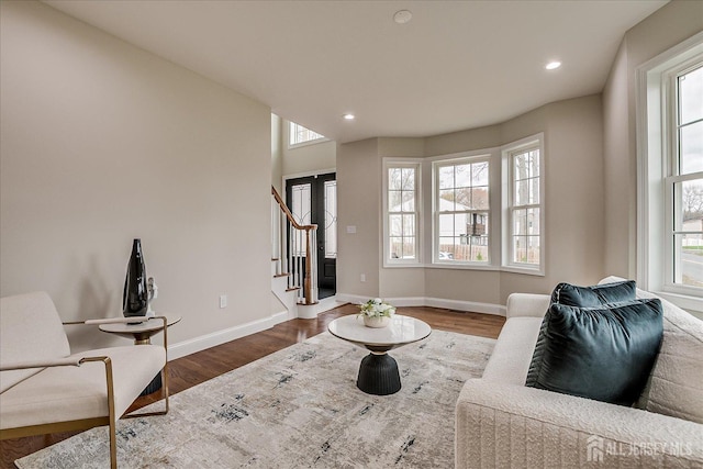 living area with wood finished floors, baseboards, recessed lighting, and stairs