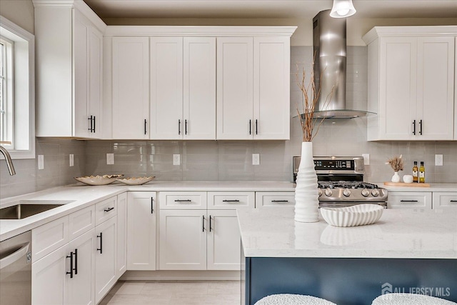 kitchen with stainless steel appliances, a sink, tasteful backsplash, white cabinetry, and wall chimney range hood