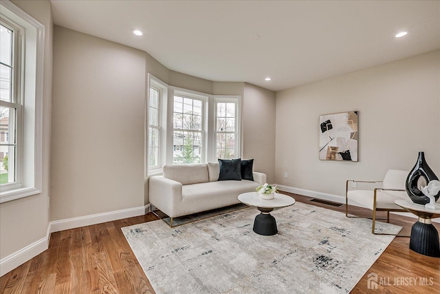 living area with recessed lighting, wood finished floors, visible vents, and baseboards