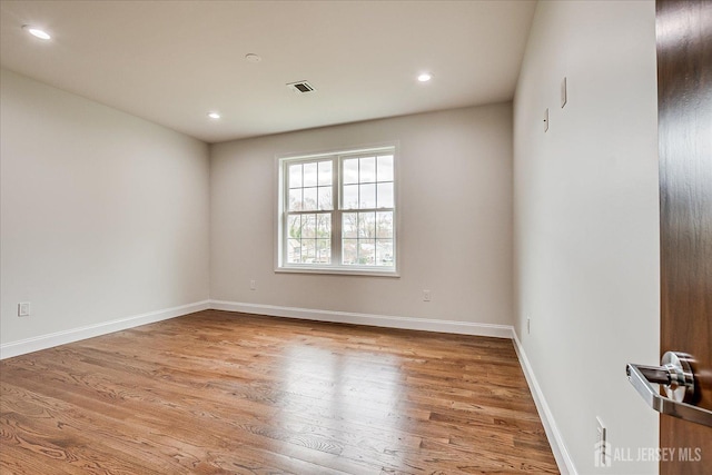 empty room featuring baseboards, recessed lighting, wood finished floors, and visible vents
