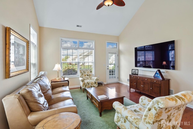 living room with visible vents, baseboards, ceiling fan, dark wood-type flooring, and high vaulted ceiling