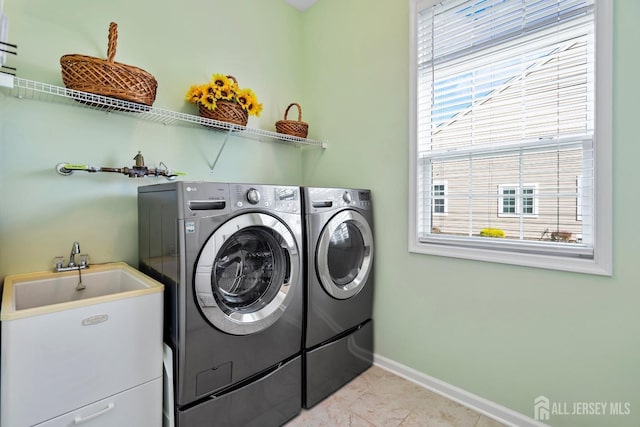 laundry room featuring light tile patterned floors, baseboards, a sink, laundry area, and washing machine and clothes dryer