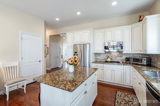 kitchen with dark wood-type flooring, decorative backsplash, white cabinets, and stainless steel appliances