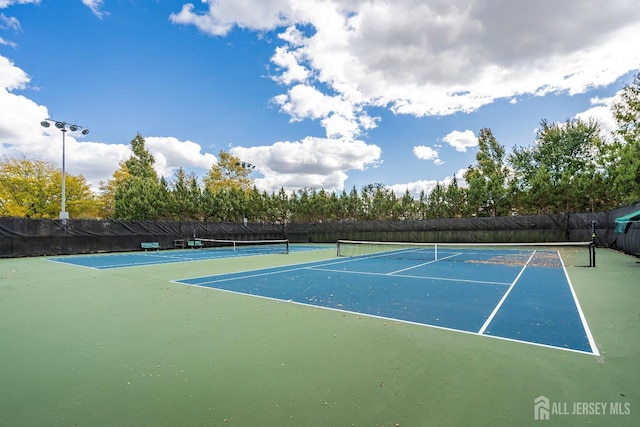 view of tennis court featuring fence and community basketball court