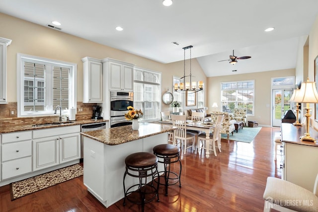 kitchen with visible vents, a sink, dark wood-style flooring, ceiling fan with notable chandelier, and stainless steel appliances