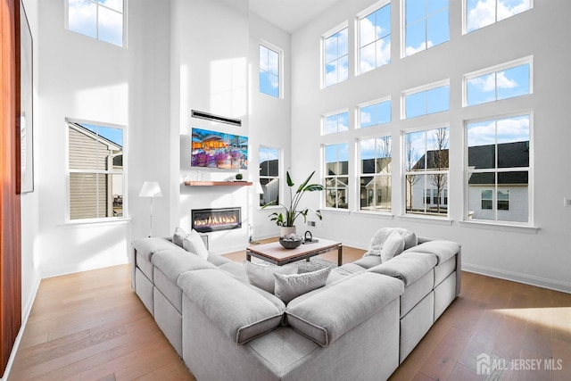 living room featuring a glass covered fireplace, hardwood / wood-style flooring, and baseboards