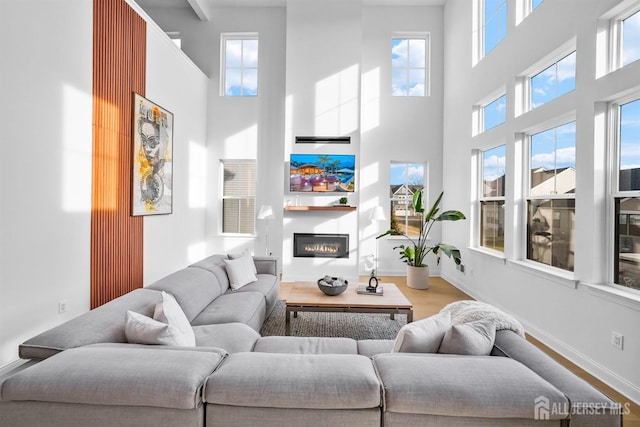 living room featuring a glass covered fireplace, wood finished floors, and baseboards