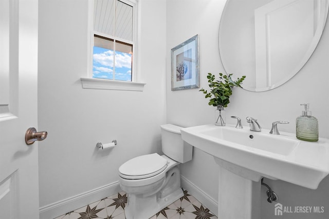 half bathroom with tile patterned floors, baseboards, and toilet