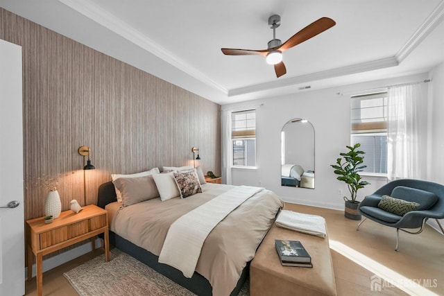 bedroom with ceiling fan, baseboards, ornamental molding, wood finished floors, and a raised ceiling