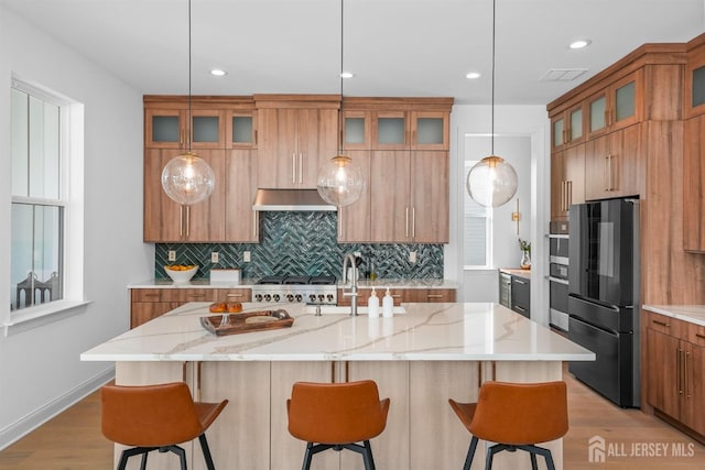 kitchen with fridge, a large island, pendant lighting, and light stone counters