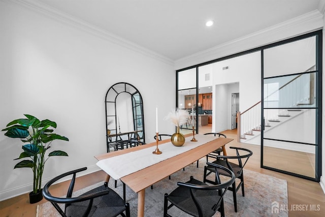 home office featuring light wood finished floors, visible vents, baseboards, and ornamental molding