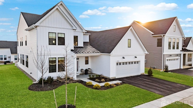 modern inspired farmhouse featuring a front yard, driveway, a standing seam roof, board and batten siding, and metal roof