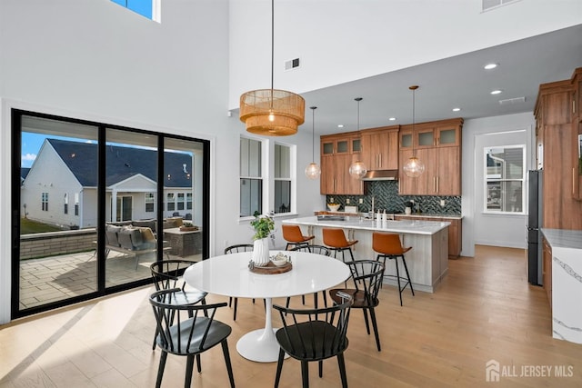 dining area featuring visible vents, recessed lighting, light wood-style floors, and a towering ceiling