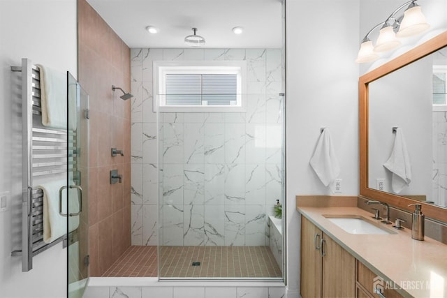 bathroom with a marble finish shower, radiator, and vanity