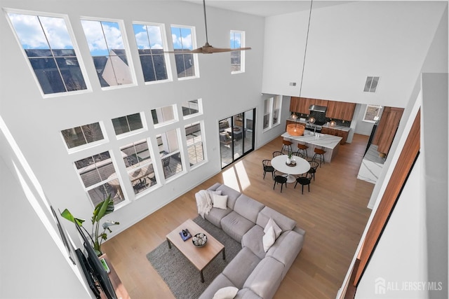 living room featuring hardwood / wood-style flooring, ceiling fan, and a high ceiling