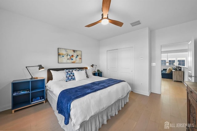 bedroom featuring visible vents, light wood-style flooring, a closet, baseboards, and ceiling fan