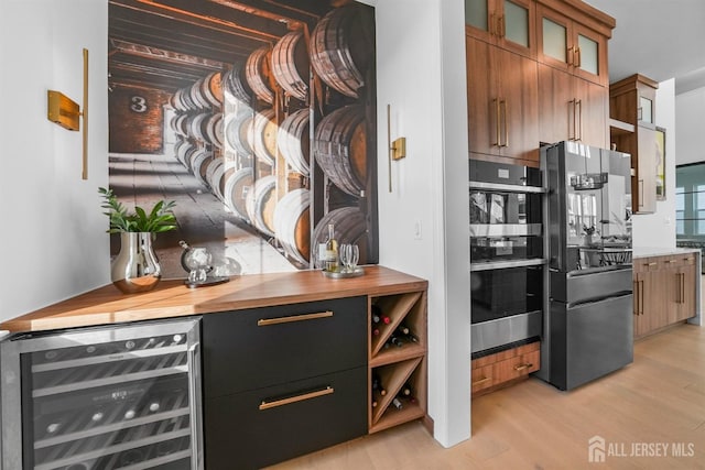 kitchen featuring light wood-type flooring, freestanding refrigerator, stainless steel double oven, wine cooler, and glass insert cabinets