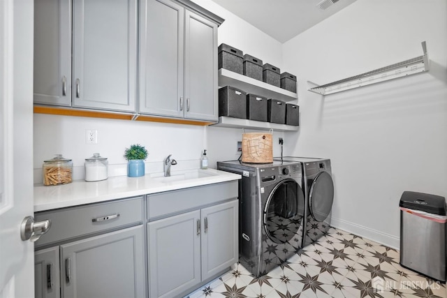 washroom with a sink, baseboards, light floors, cabinet space, and separate washer and dryer